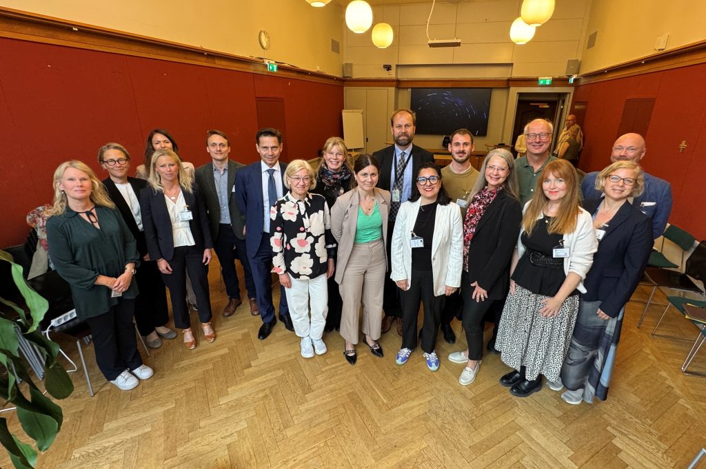 En grupp människor står tillsammans i ett rum med röda väggar